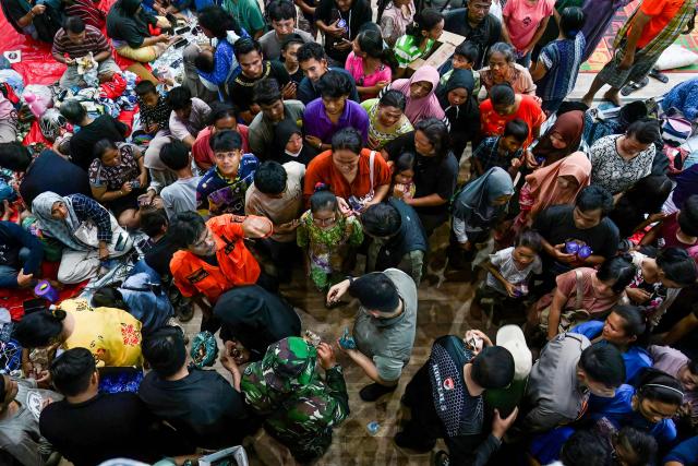 North Sumatra Governor Bobby Nasution (C) distributes meals to displaced residents at a shelter following flash floods and landslides in Pandan in Central Tapanuli, Indonesia's North Sumatra province on November 30, 2025. The death toll from floods that hit Indonesia this week has risen to more than 300 people, according to figures from the disaster agency on November 29. (Photo by YT Hariono / AFP)