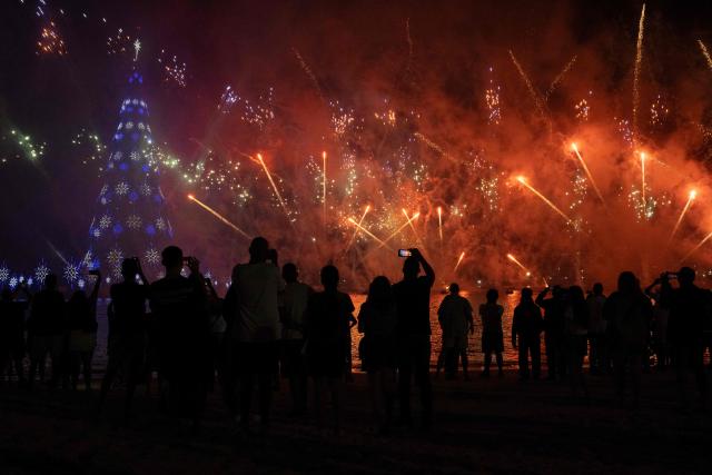 People enjoy a fireworks display next to a floating Christmas tree at Botafogo waterfront in Rio de Janeiro, Brazil on November 30, 2025. (Photo by Pablo PORCIUNCULA / AFP)