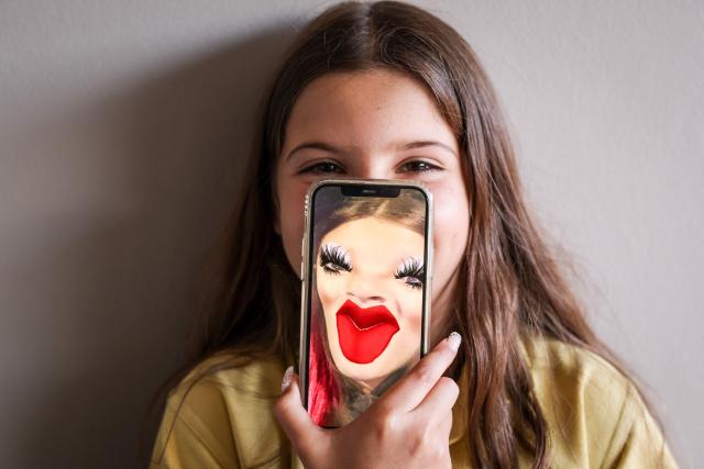 (FILES) This photo taken on October 30, 2025 shows 10-year-old Bianca Navarro posing with a screenshot of herself from Snapchat on her iPhone at her home in western Sydney. Australia's under-16 social media ban will make the nation a real-life laboratory on how best to tackle the technology's impact on young people, experts say. Those in favour of the world-first December 10 ban point to a growing mass of studies that suggest too much time online takes a toll on teen wellbeing. (Photo by David GRAY / AFP)