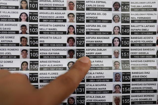 A man points at a picture of Honduras presidential candidate of the National Party Nasry Asfura displayed on a voters list at a polling station during the general election in Tegucigalpa on November 30, 2025. Hondurans voted for president on November 30, 2025, amid threats by US President Donald Trump to cut aid to the country if his preferred candidate loses. (Photo by Lucas AGUAYO / AFP)