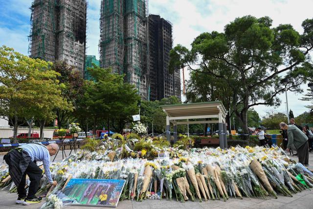 Mourners lay flowers as they pay their respects for victims at a makeshift memorial outside the Wang Fuk Court apartment blocks in the aftermath of the deadly November 26 fire in Hong Kong's Tai Po district on December 1, 2025. Police as well as Hong Kong's anti-corruption watchdog have launched investigations into the blaze that have killed at least 146 people, but a petition calling for greater accountability and demanding an independent probe was swiftly shut down as an organiser was reportedly arrested for sedition. (Photo by Peter PARKS / AFP)