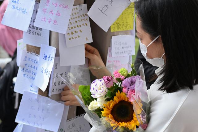 A mourner places a message for victims at a makeshift memorial outside the Wang Fuk Court apartment blocks in the aftermath of the deadly November 26 fire in Hong Kong's Tai Po district on December 1, 2025. Police as well as Hong Kong's anti-corruption watchdog have launched investigations into the blaze that have killed at least 146 people, but a petition calling for greater accountability and demanding an independent probe was swiftly shut down as an organiser was reportedly arrested for sedition. (Photo by Peter PARKS / AFP)