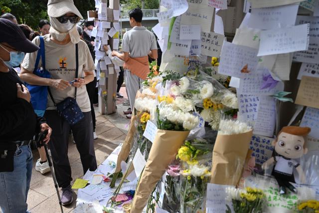 Mourners pay their respects for victims at a makeshift memorial outside the Wang Fuk Court apartment blocks in the aftermath of the deadly November 26 fire in Hong Kong's Tai Po district on December 1, 2025. Police as well as Hong Kong's anti-corruption watchdog have launched investigations into the blaze that have killed at least 146 people, but a petition calling for greater accountability and demanding an independent probe was swiftly shut down as an organiser was reportedly arrested for sedition. (Photo by Peter PARKS / AFP)