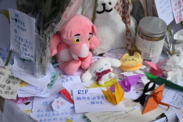 Flowers, messages and cuddly toys placed by mourners are seen at a makeshift memorial outside the Wang Fuk Court apartment blocks in the aftermath of the deadly November 26 fire in Hong Kong's Tai Po district on December 1, 2025. Police as well as Hong Kong's anti-corruption watchdog have launched investigations into the blaze that have killed at least 146 people, but a petition calling for greater accountability and demanding an independent probe was swiftly shut down as an organiser was reportedly arrested for sedition. (Photo by Peter PARKS / AFP)