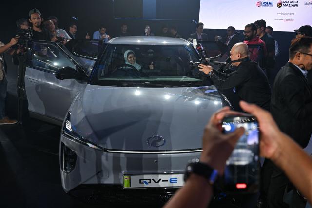 Members of the media take pictures of Perodua's first EV car during a launch event in Kuala Lumpur on December 1, 2025. (Photo by Mohd RASFAN / AFP)