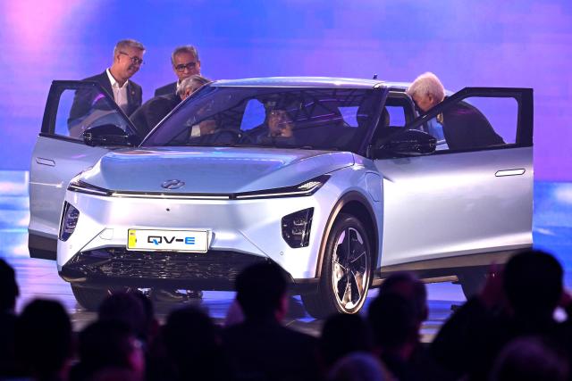 Malaysia's Prime Minister Anwar Ibrahim (C) sits inside Perodua's first EV car during a launch event in Kuala Lumpur on December 1, 2025. (Photo by Mohd RASFAN / AFP)