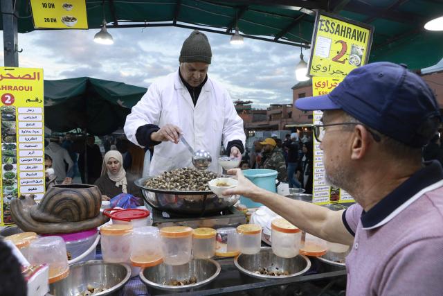 Snail vendors serve customers in Jemaa el-Fna Square or Jamaa Lafna, listed as UNESCO Cultural Heritage site, located in the heart of the Medina of the city of Marrakech on November 30, 2025. (Photo by Abdel Majid BZIOUAT / AFP)