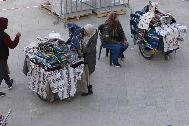 Vendors of traditional Marrakech clothing wait for customers in Jemaa el-Fna Square or Jamaa Lafna, listed as UNESCO Cultural Heritage site, located in the heart of the Medina of the city of Marrakech on November 30, 2025. (Photo by Abdel Majid BZIOUAT / AFP)