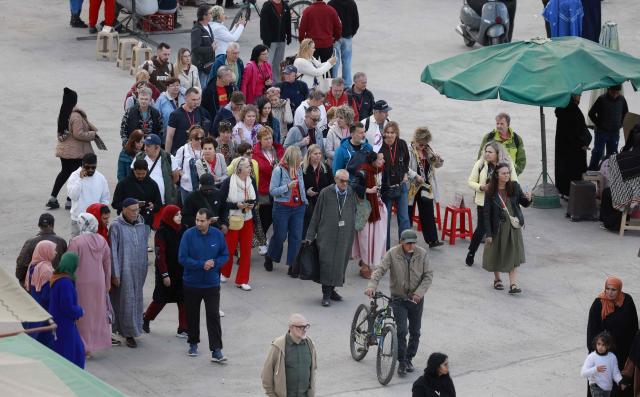 Tourists with their guide walk through Jemaa el-Fna Square or Jamaa Lafna, listed as UNESCO Cultural Heritage site, in the heart of the Medina of the city of Marrakech on November 30, 2025. (Photo by Abdel Majid BZIOUAT / AFP)