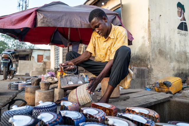 Sadiq Salisu, 20, irons a knitted cap at his stall near the Central Mosque of Minna, Nigeria on Sunday 30, November 2025.. (Photo by Light Oriye Tamunotonye / AFP)