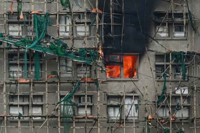 (FILES) Apartments still burn as a major fire swept through several apartment blocks at the Wang Fuk Court residential estate in Hong Kong's Tai Po district on November 27, 2025. Hong Kong police said on December 1 they had arrested a total of 13 people for manslaughter over a deadly fire that ripped through an apartment complex last week, killing at least 146. (Photo by Peter PARKS / AFP)