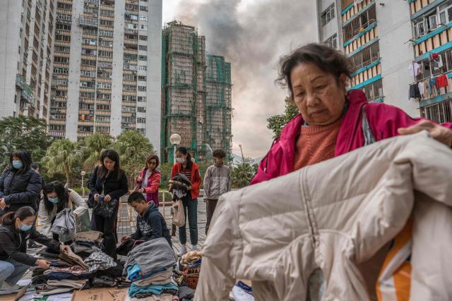 (FILES) Residents check clothing donated for them after a major fire swept through several apartment blocks at the Wang Fuk Court residential estate in Hong Kong's Tai Po district on November 27, 2025. Hong Kong police said on December 1 they had arrested a total of 13 people for manslaughter over a deadly fire that ripped through an apartment complex last week, killing at least 146. (Photo by Dale DE LA REY / AFP)