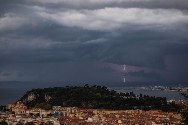 An airplane takes off as lightning illuminates the horizon in the city of Nice, in southern France, on December 1, 2025. (Photo by Valery HACHE / AFP)