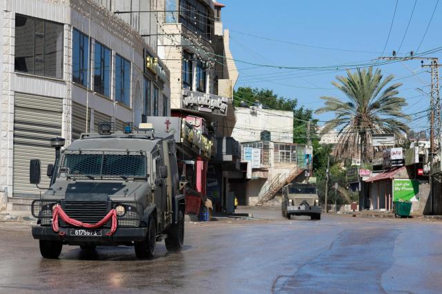 Israeli military vehicles are driven in an empty street during a military operation in the city of Tubas, north of the occupied West bank, on December 1, 2025. Israel's military launched a new operation against Palestinian armed groups in the occupied West Bank, where a local governor told AFP that Israeli forces had raided several towns. (Photo by Jaafar ASHTIYEH / AFP)