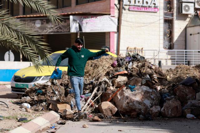 A Palestinian man walks on a barricaded street due to a curfew imposed during an Israeli military operation in the city of Tubas, north of the occupied West Bank, on December 1, 2025. Israel's military launched a new operation against Palestinian armed groups in the occupied West Bank, where a local governor told AFP that Israeli forces had raided several towns. (Photo by Jaafar ASHTIYEH / AFP)