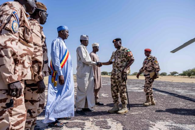 Nigerian Army Major General Saidu Tanko Audu, 56 (2nd R), the new force commander of the Multinational Joint Task Force (MNJTF) greets local authorities upon his arrival at Bol Airport in Lake Chad Province, Chad, on 26 November, 2025. The new commander-in-chief of the Multinational Joint Task Force (MNJTF) for counter-jihadist efforts in the Lake Chad Basin assured on Wednesday to AFP that securing waterways is a priority mission in this border region of Central Africa. Establishing secure navigation corridors is "one of the main priorities," according to General Saidou Tanko Audu, who has been leading the regional counter-jihadist force since mid-November. (Photo by Joris Bolomey / AFP)