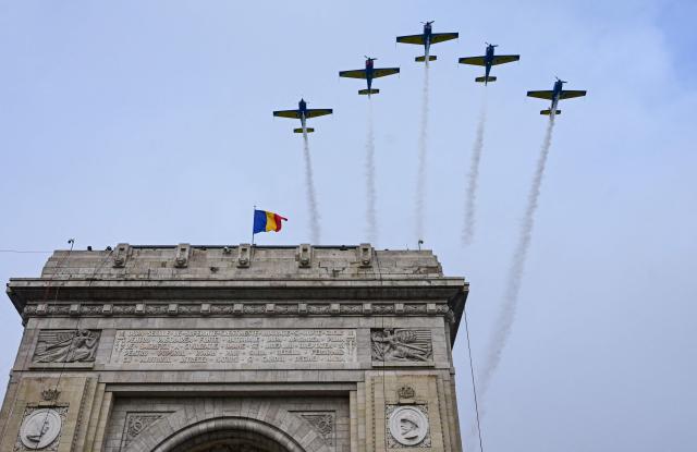 An aircraft squadron flies over the Arcul de Triumf (the Triumphal Arch) during a military parade of Romania's Army to mark the country's National Holiday in Bucharest, on December 1, 2025. A formation of acrobatic airplanes fly over the Triumph Arch during military perade on National Day of Romania in Bucharest December 1, 2025. (Photo by Daniel MIHAILESCU / AFP)