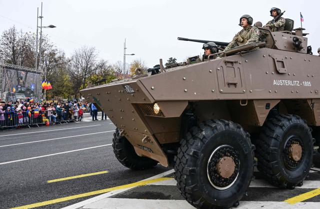 French soldiers on an armored vehicle take part in a military parade of Romania's Army to mark the country's National Holiday in Bucharest, on December 1, 2025. (Photo by Daniel MIHAILESCU / AFP)