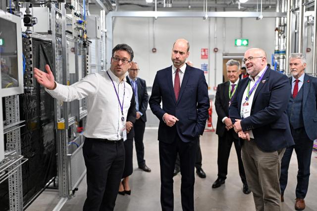 Britain's Prince William, Prince of Wales, (C) stands alongside Andrew Evans of SPTS, as John Peploe (L), Facilities Director of KLA, talks during a visit to the newly opened SPTS, a division of international semiconductor company KLA, in the city of Newport, Wales, on December 1, 2025. (Photo by Matthew Horwood / POOL / AFP)