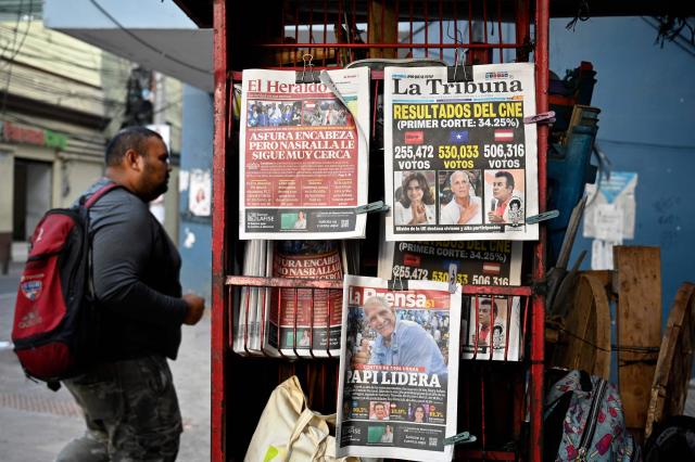 A man walks past a kiosk showing the front pages of newspapers in Tegucigalpa, on December 1, 2025, the day after the national election. Candidate Nasry Asfura, supported by US President Donald Trump, and his rival Salvador Nasralla, also from the right, are locked in a close race for victory in Honduras' presidential elections on Monday. (Photo by Orlando SIERRA / AFP)