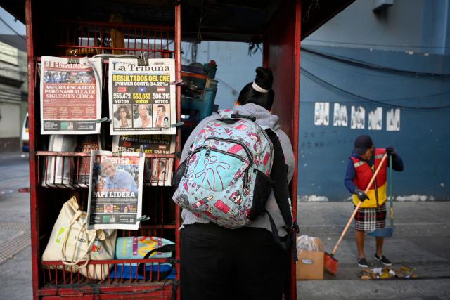 A woman stands in front of a kiosk showing the front pages of newspapers in Tegucigalpa, on December 1, 2025, the day after the national election. Candidate Nasry Asfura, supported by US President Donald Trump, and his rival Salvador Nasralla, also from the right, are locked in a close race for victory in Honduras' presidential elections on Monday. (Photo by Orlando SIERRA / AFP)
