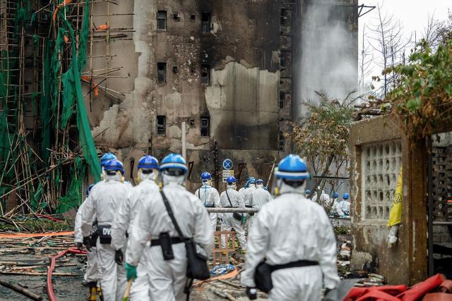 This handout photo released by the Hong Kong Police Force on December 1, 2025 shows officers from the Disaster Victim Identification Unit (DVIU) working after a deadly fire at the Wang Fuk Court residential estate in Hong Kong's Tai Po district. Authorities said on December 1 they have made a total of 13 arrests over Hong Kong's deadliest fire in decades after the blaze killed 151 people last week, a toll that could further rise. (Photo by HONG KONG POLICE FORCE / AFP)