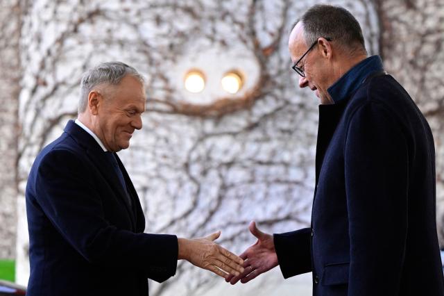 German Chancellor Friedrich Merz (R) shakes hands with Poland's Prime Minister Donald Tusk as he arrives on December 1, 2025 for a visit at the Chancellery in Berlin, Germany. (Photo by John MACDOUGALL / AFP)