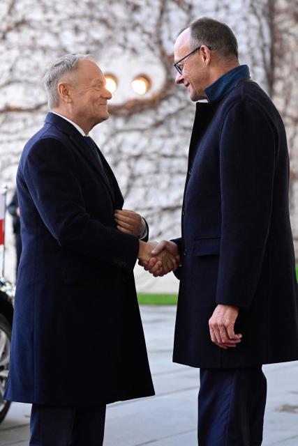 German Chancellor Friedrich Merz (R) shakes hands with Poland's Prime Minister Donald Tusk as he arrives on December 1, 2025 for a visit at the Chancellery in Berlin, Germany. (Photo by John MACDOUGALL / AFP)