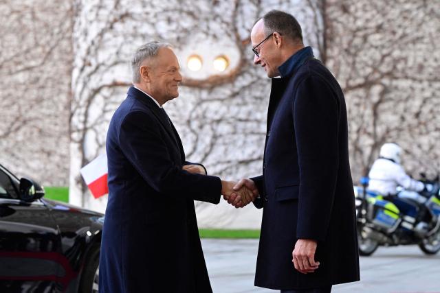 German Chancellor Friedrich Merz (R) shakes hands with Poland's Prime Minister Donald Tusk as he arrives on December 1, 2025 for a visit at the Chancellery in Berlin, Germany. (Photo by John MACDOUGALL / AFP)