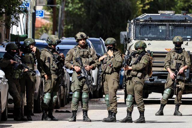 Israeli soldiers take positions during a raid in Ramallah, in the occupied West Bank on December 1, 2025. (Photo by Zain JAAFAR / AFP)
