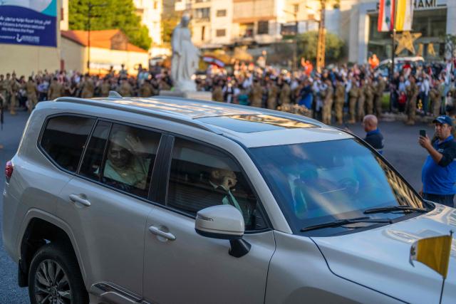 Pope Leo XIV waves at cheering crowds as his motorcade passes through Jounieh, north of Beirut, on December 1, 2025. Leo prayed for peace in Lebanon and the region on December 1 on day two of his trip to the multi-confessional country, with joyful Lebanese welcoming the pontiff at two famous pilgrimage sites. (Photo by Jewel SAMAD / AFP)