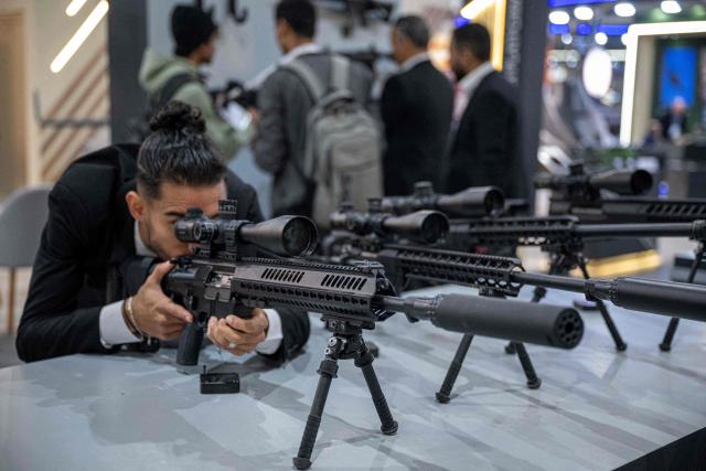 A visitor inspects a sniper rifle during the opening day of the 4th edition of Egypt Defence Expo (EDEX-2023), at Cairo International Exhibition Centre, in Cairo on December 1, 2025. (Photo by Khaled DESOUKI / AFP)