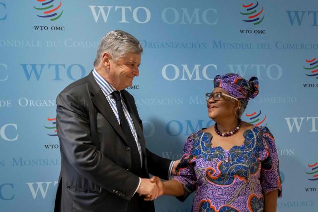France's junior Minister in charge of external trade Nicolas Forissier (L) shakes hands with World Trade Organization (WTO) Director-General Ngozi Okonjo-Iweala after a meeting at the WTO's headquarters in Geneva on December 1, 2025. (Photo by Fabrice COFFRINI / AFP)