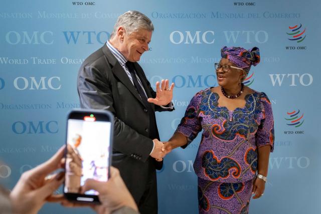 France's junior Minister in charge of external trade Nicolas Forissier (L) waves as he shakes hands with World Trade Organization (WTO) Director-General Ngozi Okonjo-Iweala after a meeting at the WTO's headquarters in Geneva on December 1, 2025. (Photo by Fabrice COFFRINI / AFP)
