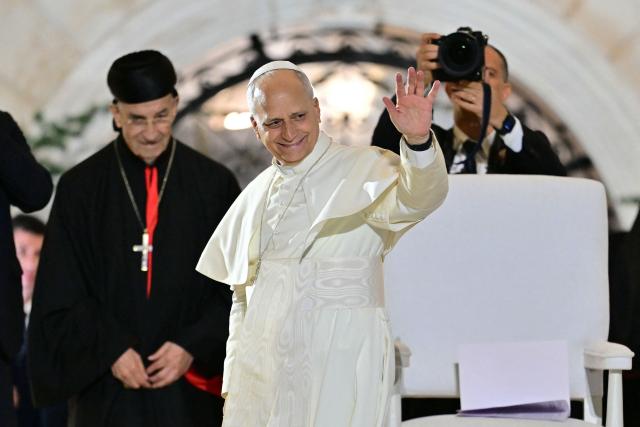Pope Leo XIV (C) waves as he stands next to Lebanon's Maronite patriarch, Cardinal Beshara Rai, at the end of a gathering with youths at the Maronite Patriarchate in Bkerke, north of the capital Beirut, on December 1, 2025. Leo prayed for peace in Lebanon and the region on December 1 on day two of his trip to the multi-confessional country, with joyful Lebanese welcoming the pontiff at two famous pilgrimage sites. (Photo by Giuseppe CACACE / AFP)