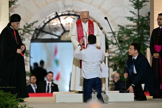 A man kneels before Pope Leo XIV as Lebanon's Maronite patriarch Cardinal Beshara Rai (L) looks on at the end of a gathering with youths at the Maronite Patriarchate in Bkerke, north of the capital Beirut, on December 1, 2025. Leo prayed for peace in Lebanon and the region on December 1 on day two of his trip to the multi-confessional country, with joyful Lebanese welcoming the pontiff at two famous pilgrimage sites. (Photo by Giuseppe CACACE / AFP)