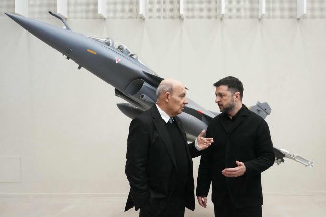 CEO of French aircraft manufacturer Dassault Aviation Eric Trappier (L) greets Ukraine's President Volodymyr Zelensky at the Dassault Aviation plant, in Cergy, northwest of Paris, on December 1, 2025. President Volodymyr Zelensky sought to reinforce European support for Ukraine at a potentially pivotal moment in Kyiv's battle against the Russian invasion, during a meeting on December 1, 2025 with France's President Emmanuel Macron in Paris as Washington pushed a plan to end the war. (Photo by Dimitar DILKOFF / POOL / AFP)
