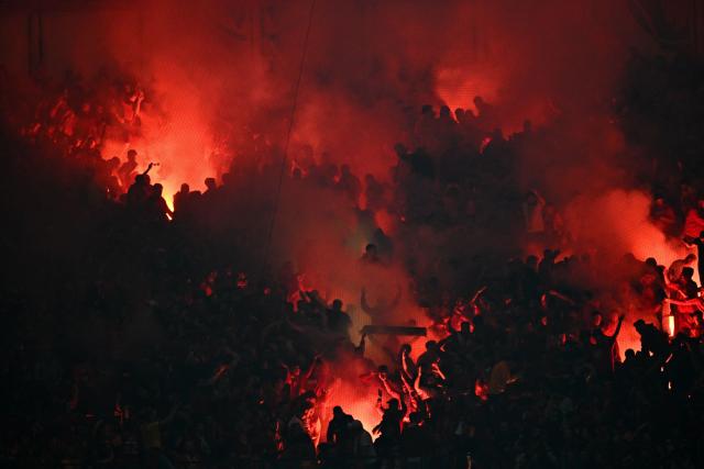 Galatasaray's light smoke flares as they celebrate their team's first goal during the Turkish Super lig football match between Fenerbahce and Galatasaray at the Fenerbahce Sukru Saracoglu stadium in Istanbul, on December 1, 2025. (Photo by Ozan KOSE / AFP)