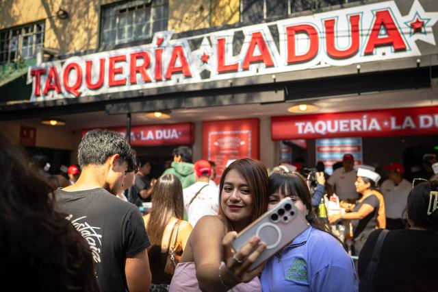 Fans of British-Albanian singer-songwriter Dua Lipa make a selfie during the opening of the pop-up taco shop, Taqueria La Dua, in Mexico City on December 1, 2025. The pop-up celebrates Dua Lipa's arrival in Mexico, the last stop on her international Radical Optimism Tour. (Photo by Carl de Souza / AFP)