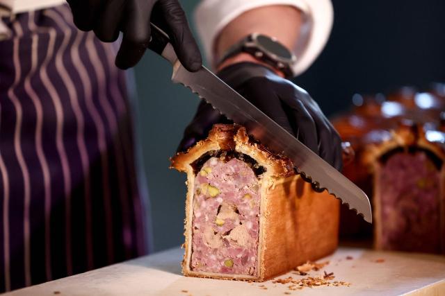French chef Nicolas Delaroque representing Canada and the USA, cuts into slices his pate-croute creation during the 16th Edition of the 2025 Pate-Croute World Championship, in Lyon, central-eastern France, on December 1, 2025. (Photo by Alex MARTIN / AFP)
