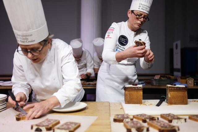 TOPSHOT - French chef Emeline Aubry (R) representing France, cuts into slices his pate-croute creation during the 16th Edition of the 2025 Pate-Croute World Championship, in Lyon, central-eastern France, on December 1, 2025. (Photo by Alex MARTIN / AFP)