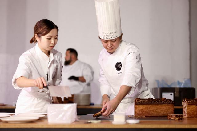 Japanese chef Sho Ito (R) representing Japan, cuts his pate-croute creation during the 16th Edition of the 2025 Pate-Croute World Championship, in Lyon, central-eastern France, on December 1, 2025. (Photo by Alex MARTIN / AFP)