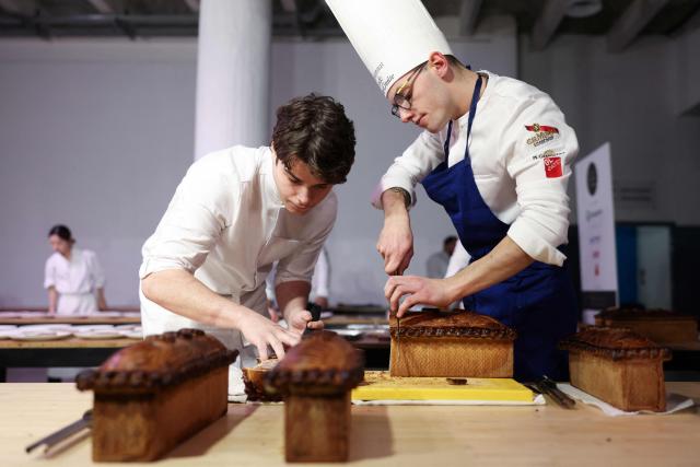French chef Clement Destrebecq (R) representing France, cuts into slices his pate-croute creation during the 16th Edition of the 2025 Pate-Croute World Championship, in Lyon, central-eastern France, on December 1, 2025. (Photo by Alex MARTIN / AFP)