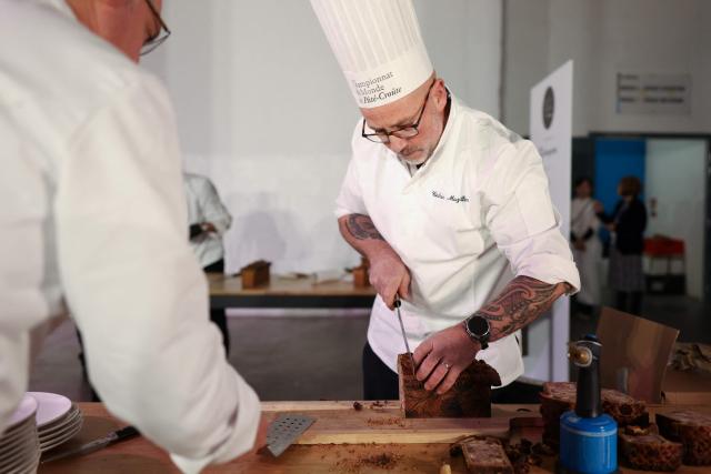 French chef Cedric Maziller (R) representing France, cuts into slices his pate-croute creation during the 16th Edition of the 2025 Pate-Croute World Championship, in Lyon, central-eastern France, on December 1, 2025. (Photo by Alex MARTIN / AFP)