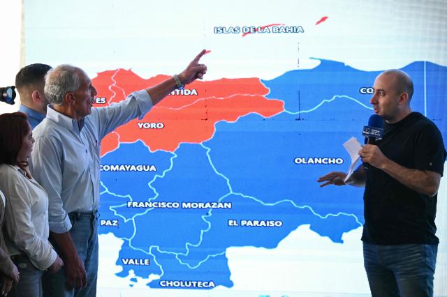 Honduras' presidential candidate of the National Party Nasry Asfura (2-L) point at a screen projecting a map of Honduras during a press conference in Tegucigalpa on December 1, 2025, a day after the presidential election. Candidate Nasry Asfura, supported by US President Donald Trump, and his rival Salvador Nasralla, also from the right-wing, are locked in a close race for victory in Honduras' presidential elections on Monday. (Photo by Marvin RECINOS / AFP)