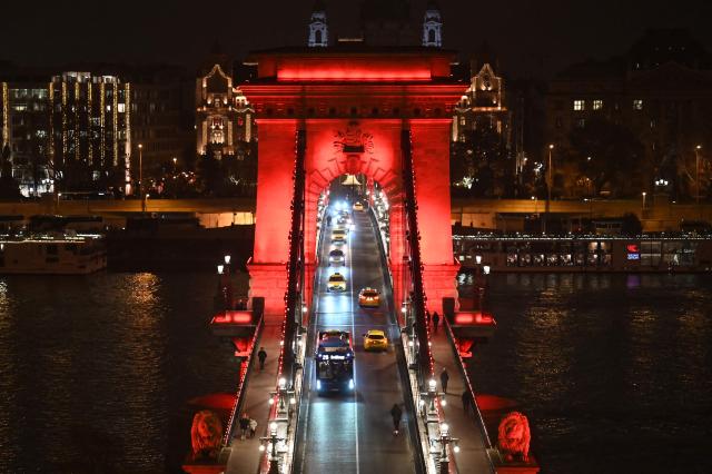 The Szechenyi Chain Bridge, Hungary's oldest bridge, is illuminated to commemorate World AIDS Day in Budapest on December 1, 2025. This international health day has been observed annually since 1988 to raise awareness about the AIDS pandemic caused by the spread of HIV infection, show support for people living with HIV, and to commemorate those who have died of the disease. (Photo by Attila KISBENEDEK / AFP)