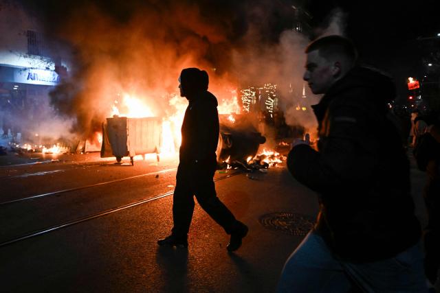 Protesters walk past burning trash cans during an anti-government protest in Sofia on December 1, 2025. Tens of thousands of people held anti-government protests in Bulgaria on Monday, widening an anti-corruption movement sweeping the European Union's poorest country as it prepares to adopt the euro. (Photo by Nikolay DOYCHINOV / AFP)