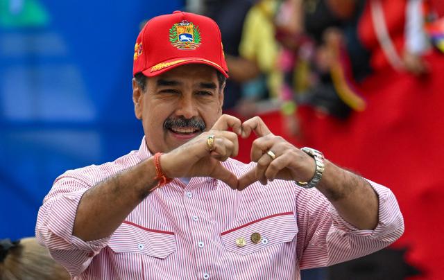 Venezuela’s President Nicolбs Maduro makes a heart with his fingers for his supporters during a rally in Caracas on December 1, 2025. Venezuela does not want "a slave's peace," President Nicolas Maduro told thousands of supporters during a rally, referring to a US military deployment he said has been "testing" his country for 22 weeks. (Photo by Juan BARRETO / AFP)
