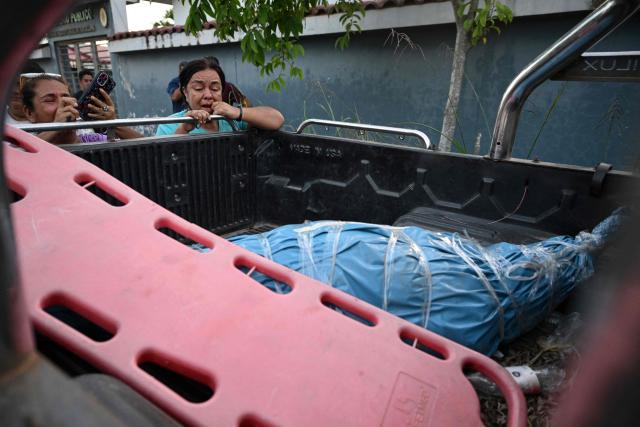 A woman reacts in front of some of the bodies of victims from the wreckage of a vessel involved in an accident at the port of Iparia, outside the Manantay morgue in Pucallpa, in the Ucayali department of Peru’s central jungle, on December 1, 2025. At least 12 people, including three children, died when a landslide buried two boats docked at a river port in central Peru, with dozens of others missing, officials said. (Photo by Hugo Alejos / AFP)
