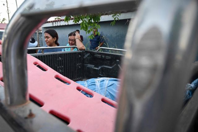Women react in front of some of the bodies of victims from the wreckage of a vessel involved in an accident at the port of Iparia, outside the Manantay morgue in Pucallpa, in the Ucayali department of Peru’s central jungle, on December 1, 2025. At least 12 people, including three children, died when a landslide buried two boats docked at a river port in central Peru, with dozens of others missing, officials said. (Photo by Hugo Alejos / AFP)